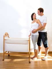 Couple with pregnant woman hug with baby cradle