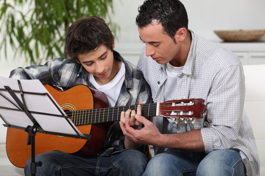 Father teaching son the guitar