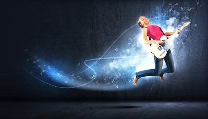 Obraz na płótnie Canvas młoda kobieta gra na gitarze elektro i skakanie