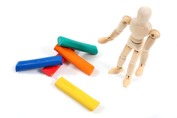 Manikin man standing at colourfull clay bars