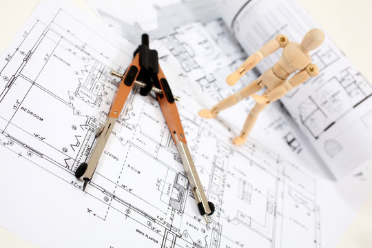 Man standing on building plans looking at measuring instrument