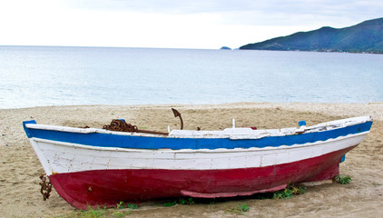 fishing boat on sand with cloudy blue sky and water