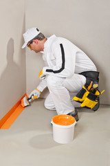 worker brush waterproofing around the wall and floor