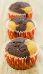 A row of chocolate and vanilla muffins on a wooden background