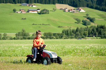 Kid playing with tractor toy outdoors.