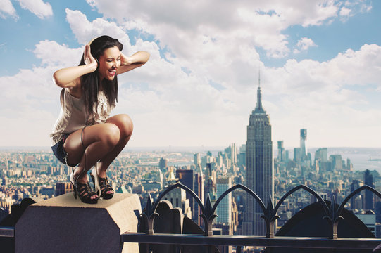 Beautiful girl listening to music standing on the rooftop 