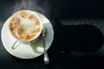Warm cup of coffee on a table with a pattern