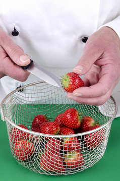 K&ouml;chin bei der Zubereitung von Erdbeeren mit einem K&uuml;chenmesse