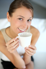 Attractive woman relaxing in sofa with cup of tea