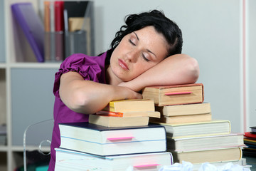 Overworked woman sleeping on a stack of books