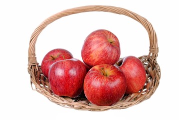 red apples in a straw basket, isolated on white