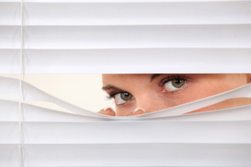 Woman peering through blinds