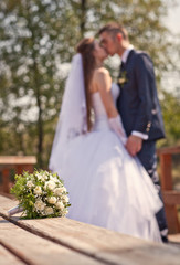 Wedding bouquet on a background of the bride and groom (bokeh)