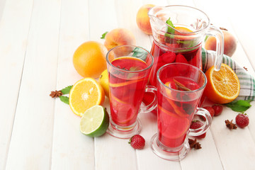 sangria in jar and glasses with fruits, on white wooden table
