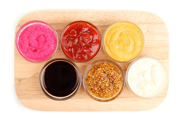 various sauces on chopping board isolated on white