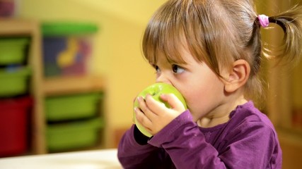 Babies and food, female child eating green apple at school - Powered by Adobe