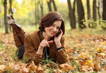 woman calling by phone in autumn park