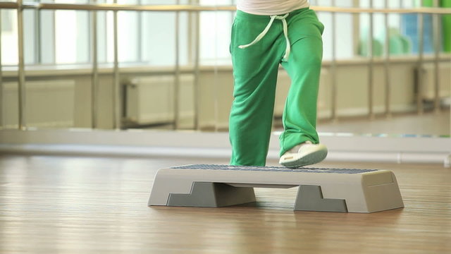 Woman training on step board in sport gym