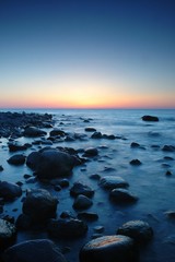 Fototapeta na wymiar Clear sky after sunset at coast with rocks in water