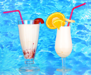 Delicious milk shake with fruit on table on blue sea background