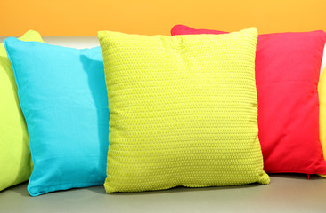 Colorful pillows on couch on yellow background