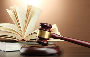 wooden gavel and books on wooden table,on brown background