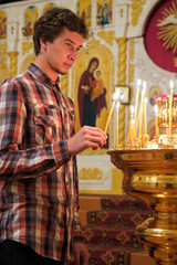 Young man lighting a candle in the church.