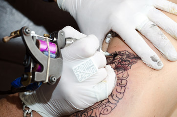 Tattoo artist makes the tattoo on arm