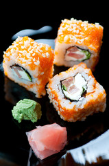 Black plate with Geisha rolls, wasabi and ginger, close-up