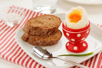 Soft-boiled egg in a red egg cup and whole grain bread