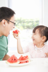 happy little girl with father eating fruits