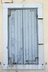 faded light blue grey painted wooden closed shutters in mediteranean doorway