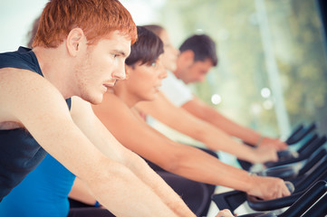 Fototapeta na wymiar Group of five people in the gym, exercising their legs doing car