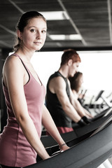 Fototapeta na wymiar Running on treadmill in gym or fitness club - group of women and
