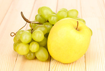 Naklejka na ściany i meble ripe sweet grapes and apple on wooden background