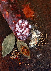 italian salami with spice on wood background