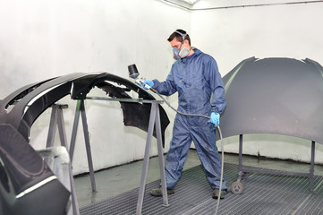 Worker painting car parts.
