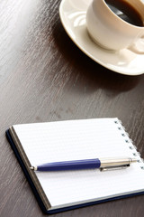 A cup of coffee and a notebook with a pen