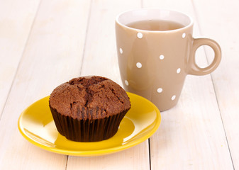 Fresh muffin with tea on wooden background