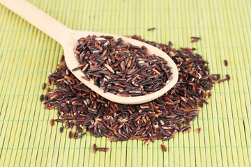 black rice  in wooden  spoon on bamboo mat