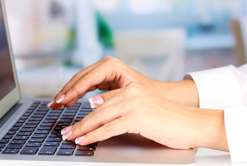 Hands typing on laptop keyboard close up