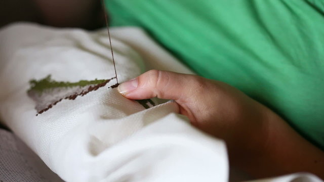 Woman hands doing cross-stitch.