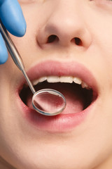 A dentist examinig patient's teeth, close-up, image