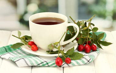 cup of tea with hip roses, on wooden table