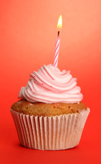 tasty birthday cupcake with candle, on red background