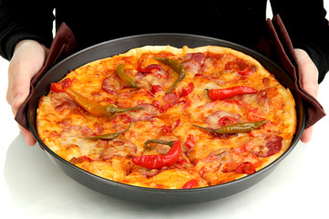 hands holding pepperoni pizza in pan close-up