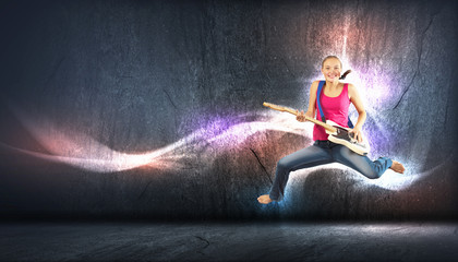 young woman playing on electro guitar and jumping