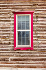 Red framed window in log house wall architecture