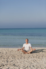 Fototapeta na wymiar Mann macht yoga Sport am Strand Hochformat