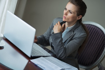 Thoughtful business woman sitting at desk in hotel room